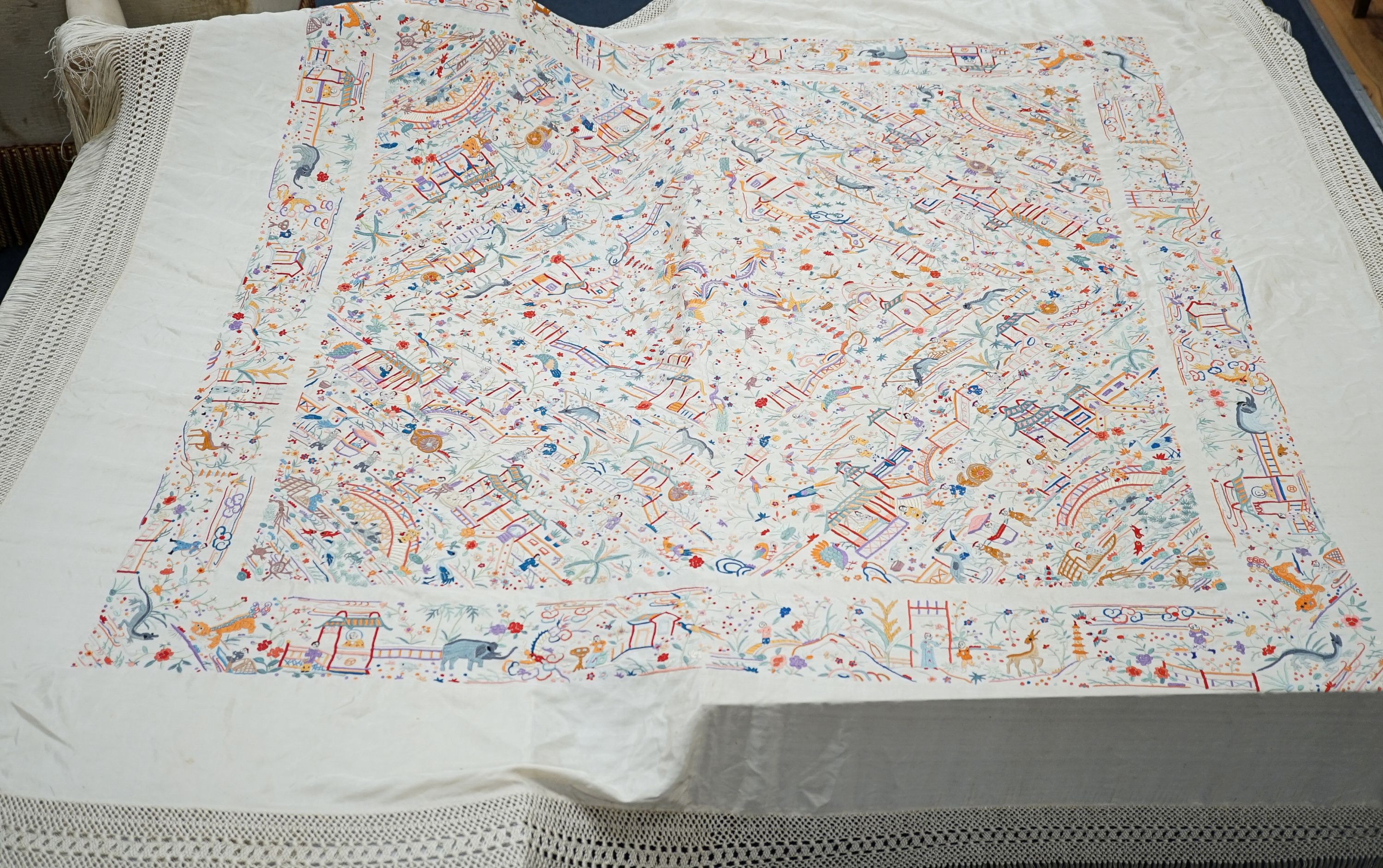 A Chinese cream silk shawl with fine multi coloured all over embroidery depicting figurative scenes and animals